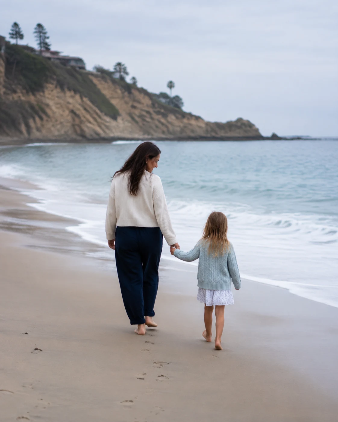 A mother and daughter walking beside the California ocean